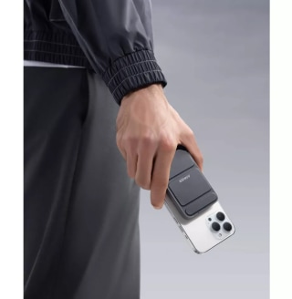 Hand holding phone with Anker magnetic portable charger attached.