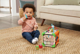 Child playing with LeapFrog Touch & Learn Wooden Activity Cube.