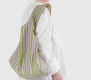 Model wearing white shirt and carrying green and pink bag on shoulder