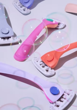 Billize razors laid on table with bubbles floating around them.