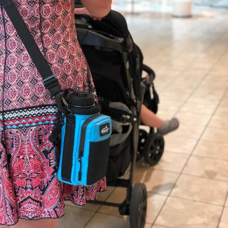 Woman wearing blue Arca Hydro Carrier while pushing a stroller. 