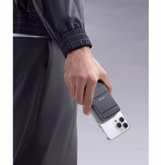 Hand holding phone with Anker magnetic portable charger attached.