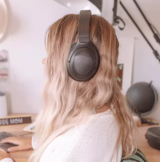 Woman with dirty blond hair wearing Puro Sound Labs PurePro headphones.