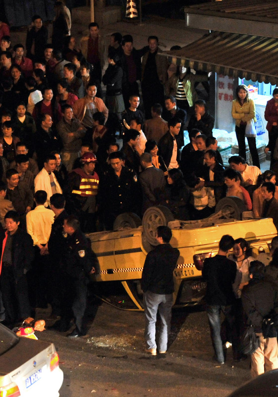 Image: Chinese police arrive to inspect an overturned taxi after a mob of angry taxi drivers