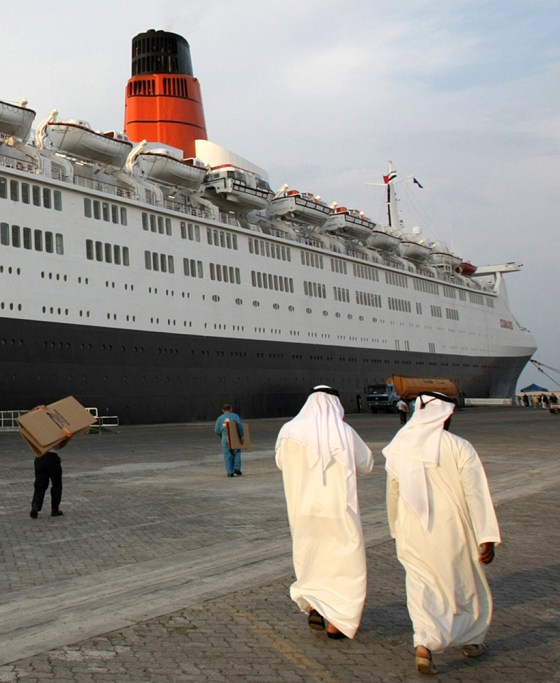 Image: Emirati men walk past the Queen Elizabeth 2