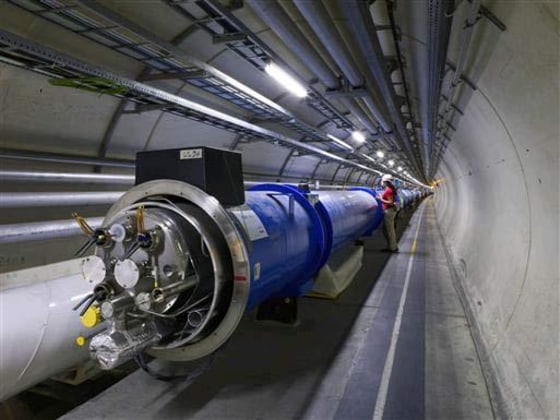An employee inside the Large Hadron Collider — a 17-mile-long particle accelerator buried underground near Geneva — works on the large magnets that guide particles around the LHC loop.