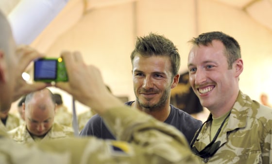 Image: Britain's soccer player Beckham has his photograph taken with a soldier from from 67 Squadron, 6 Regiment RLC, during a visit to Camp Bastion in Afghanistan