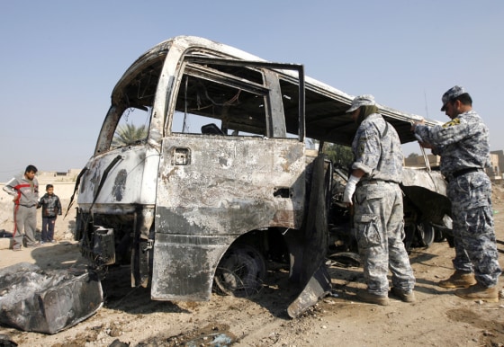 Image: Policemen inspect a burnt bus at the site of a bomb attack in eastern Baghdad