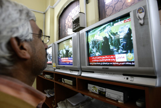 Image: An Iraqi man watches a row of televisions