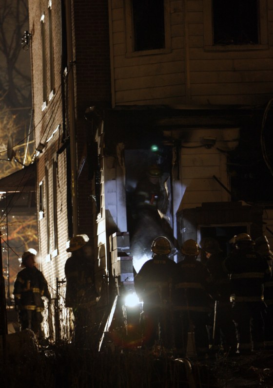 Firefighters gather at the scene of a house fire in southwest Philadelphia on Saturday, apparently caused by an exploding kerosene heater that killed seven people.