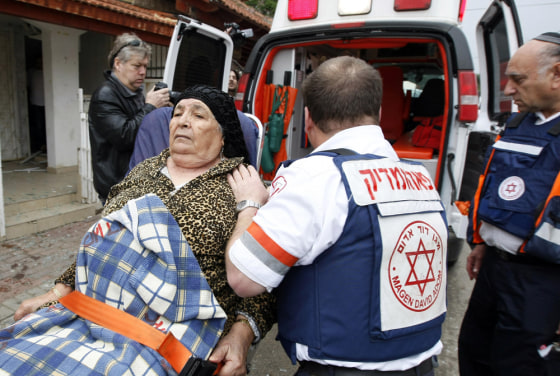 Image: Israeli paramedics evacuate an Israeli woman in shock following a rocket attack on the southern Israeli city of Sderot