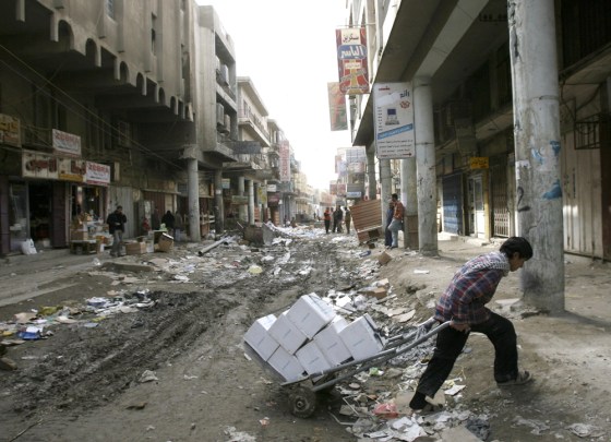 Image: a man pulls a cart through a street