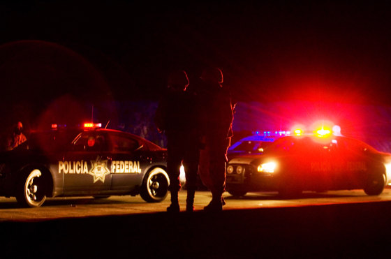 Image: Soldiers patrol as federal police vehicles are inspected at a military check point on the outskirts of Tijuana