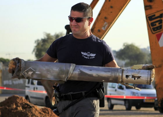 Image: An Israeli police officer carries the remains of a rocket