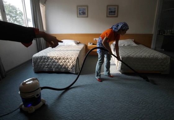 Image: Xiong Xuhua is taught by her teacher how to clean a room at a school for domestic workers in China's southern city, Guangzhou.