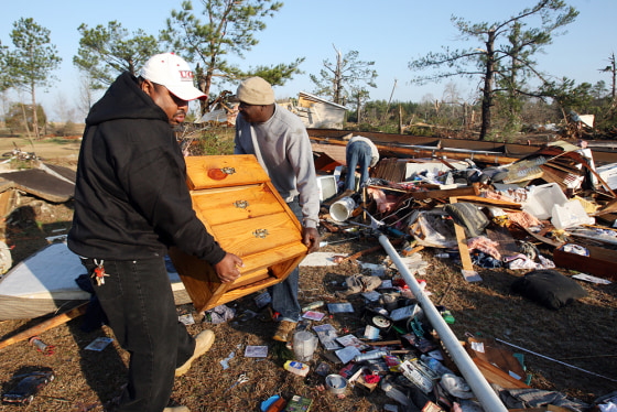 Image: Marvin Kinnett, left, and Gregory Ingram salvage a piece of furniture