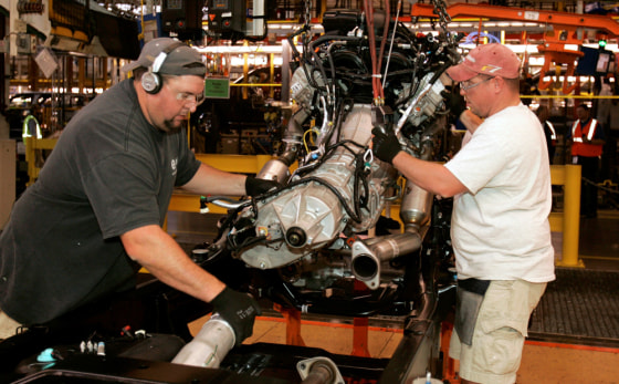 Image: Ford assemblymen mesh the engine to the drive shaft on the 2009 Ford F150 truck.