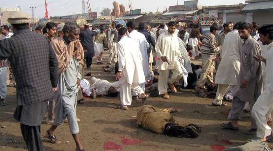 Image: People look at victims of suicide bombing in Pakistan