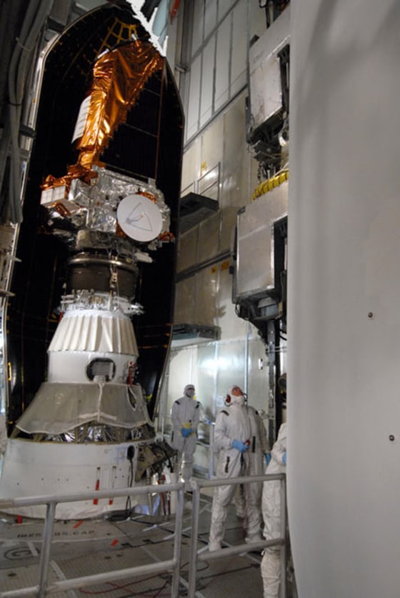 On Launch Pad 17-B at Cape Canaveral Air Force Station in Florida, workers watch closely as the second half of the fairing is moved into the mobile service tower for placement around NASA's Kepler spacecraft (left) to complete encapsulation on Feb. 26, 2009. Credit: NASA/Jack Pfaller