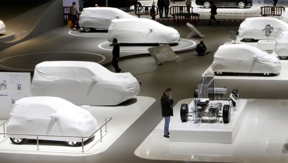 Image: Visitors walk past covered cars