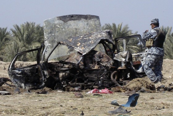 Image: A policeman inspects the wreckage of a vehicle used in a car bomb attack in Hamza