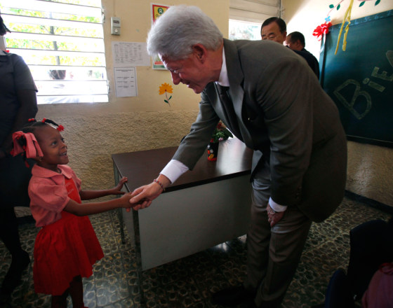 Image: Former U.S. President Bill Clinton greets a student as he visits a school in Cite Soleil in Port-au-Prince.