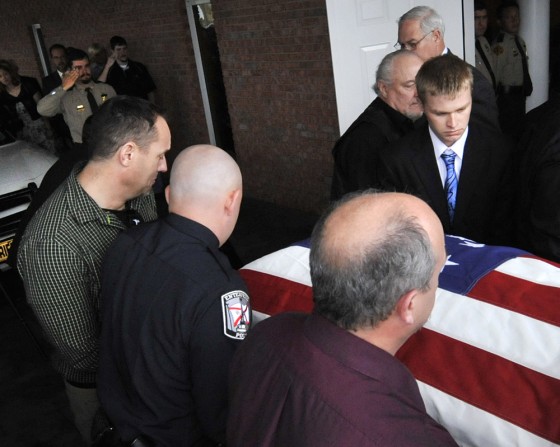 Image: Sheriff's deputy Josh Myers, upper right, salutes the casket bearing his wife and 18-month-old daughter