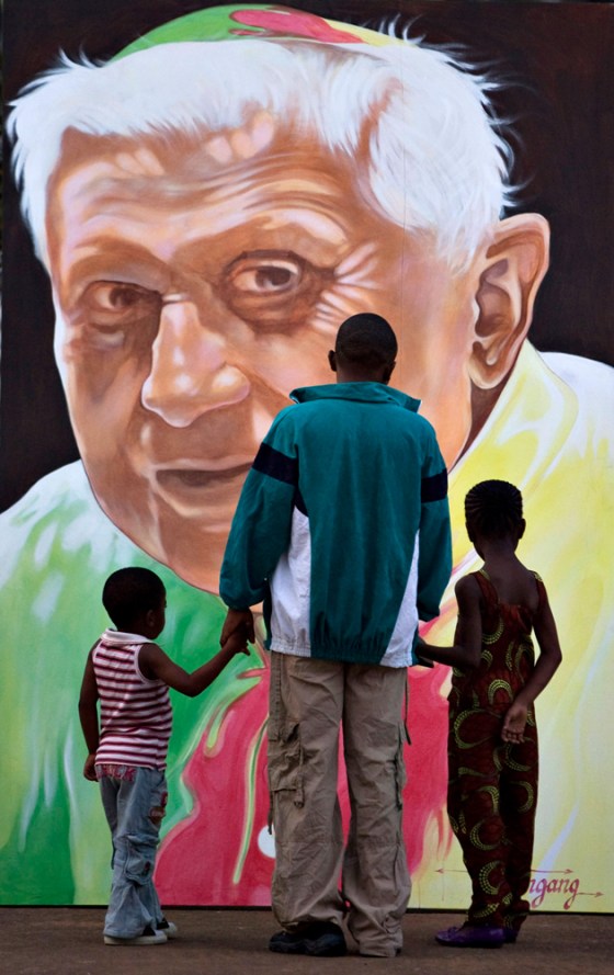 Image: A family looks at a portrait of Pope Benedict in Yaounde, Africa