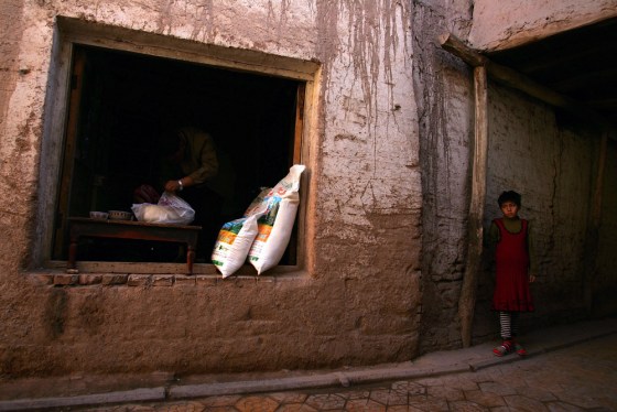 Image: A Chinese ethnic minority child stands next to a shop in Kashgar city