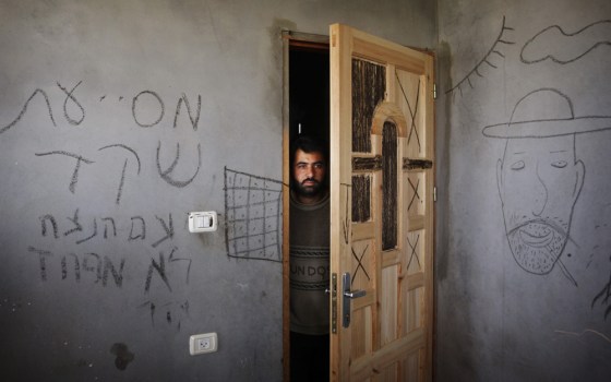 Image: A Palestinian man looks through a door as he stands in a home in Gaza.