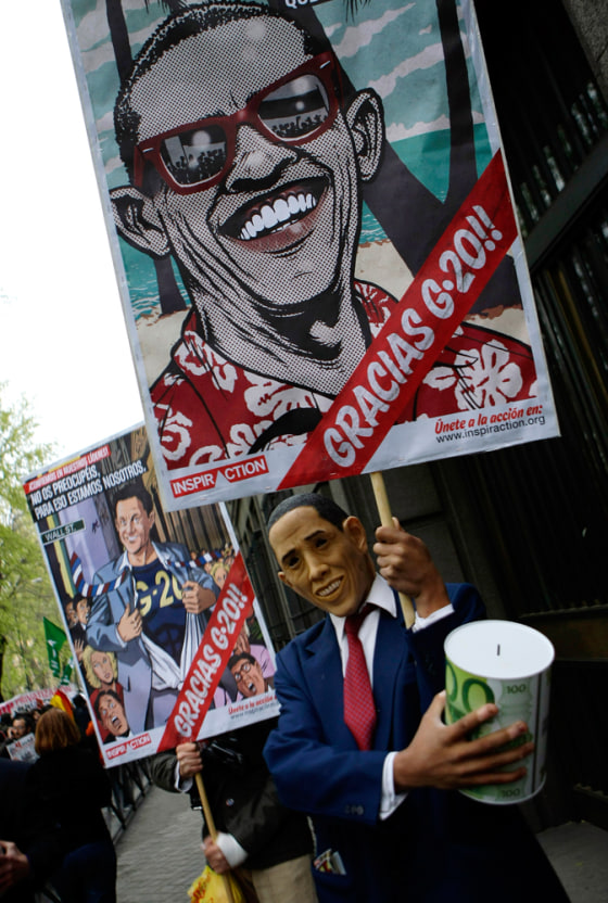 Man wearing mask depicting U.S. President Obama holds banner during demonstration against economic crisis and upcoming G20 meeting in Madrid