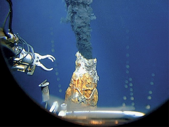 This 1997 photo released by the Woods Hole Oceanographic Institution shows the robotic arm of an unmanned aquatic vehicle reaching toward a hydrothermal vent in the east Pacific Ocean far off the coast of Chile.