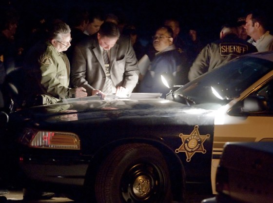 Image: Investigators use lights from a Riverside Sheriff's car to hold a meeting