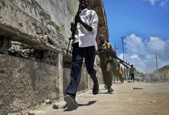 Image: Militiamen run in a street during a fire fight against Government troops