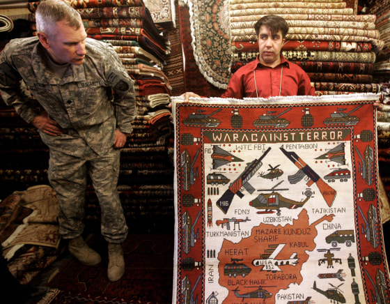 Zulmai, an Afghan Carpet seller, displays his "war rug" featuring a variety of weapons to Army Lt. Col. Chris Kubik at his shop in Camp Eggers, the U.S. base in Kabul, Afghanistan, Thursday, March 12.