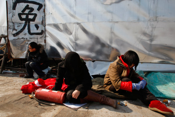 Workers of a destroyed business sit in protest next to the Chinese character for "Injustice" in February as they petition for help ahead of the annual meeting of the Chinese legislature in Beijing.