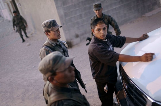 Image: An alleged gang member is detained by soldiers