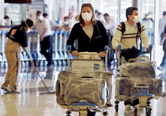 Image: Passengers wearing protective masks arrive at Buenos Aires' airport
