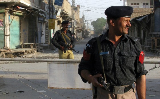 Image: Pakistani policemen stand guard on the streets during a curfew in Bannu