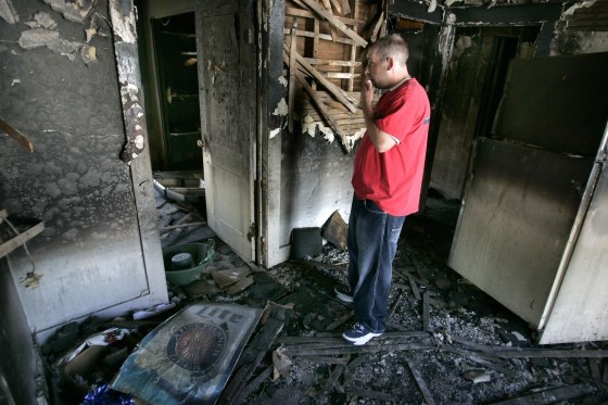 Image: Elmer Crawley, Gordy Yoesting's half-brother, looks over the burned remains of the home in Flint, Mich.