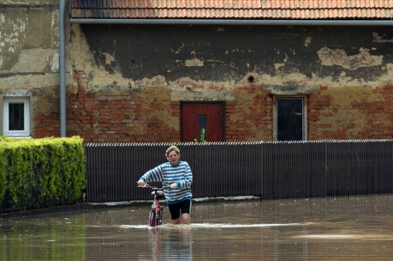 Image:A woman pushes her bicycle through a flooded street