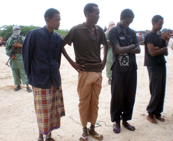 Image: Four men sentenced to have a hand and foot cut off stand in a square in north of Mogadishu, Somalia