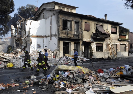 Image: Rescuers walk by the rubble of a collapsed house in Viareggio