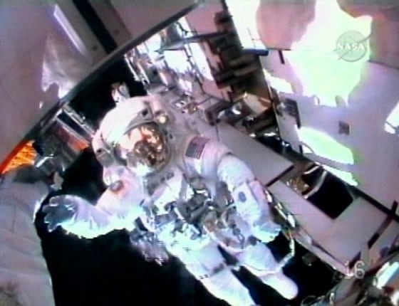 NASA astronaut Christopher Cassidy waves while in view of crewmate Dave Wolf's helmet-cam during Wednesday's spacewalk at the international space station. The spacewalk ended early because of rising carbon dioxide levels in Cassidy's suit.
