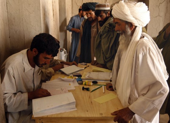 Image: Afghan men line up to receive their voter registration cards for the upcoming presidential election, in Babaji village in Helmand province