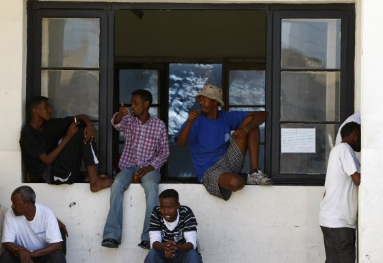Image: African immigrants and refugees sit on a window sill after a protest outside Valletta