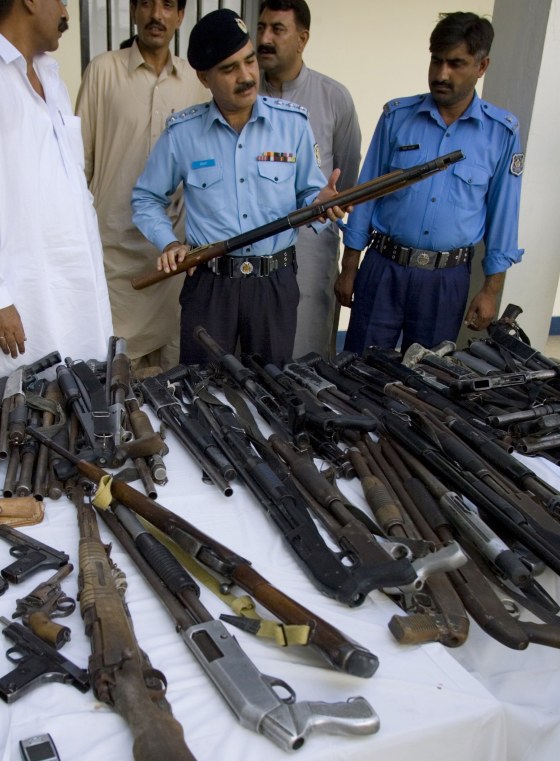 Image: Pakistani police officer inspects confiscated weapons