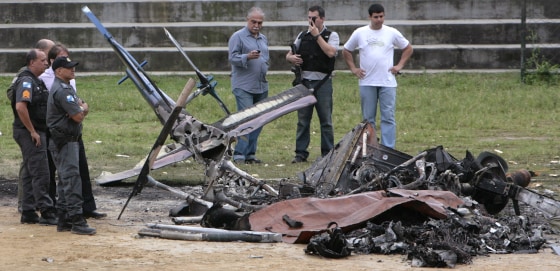 Image: Police inspect the remains of one of their crime-fighting helicopters lying in a soccer field after it was shot down in Rio de Janeiro
