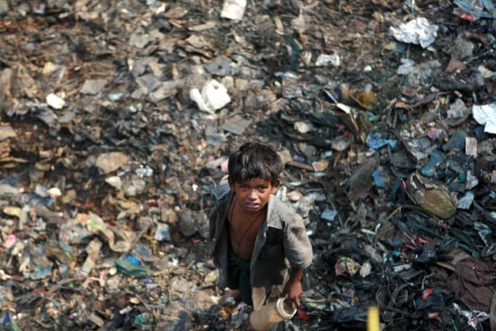 Image: A street child stands on a pile of garbage in Mumbai, India.