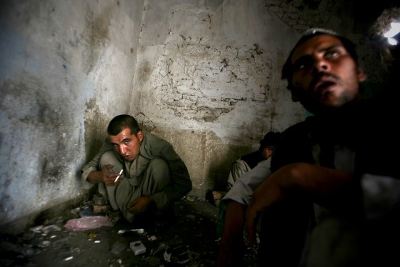 Image: Opium addicts squat on the floor